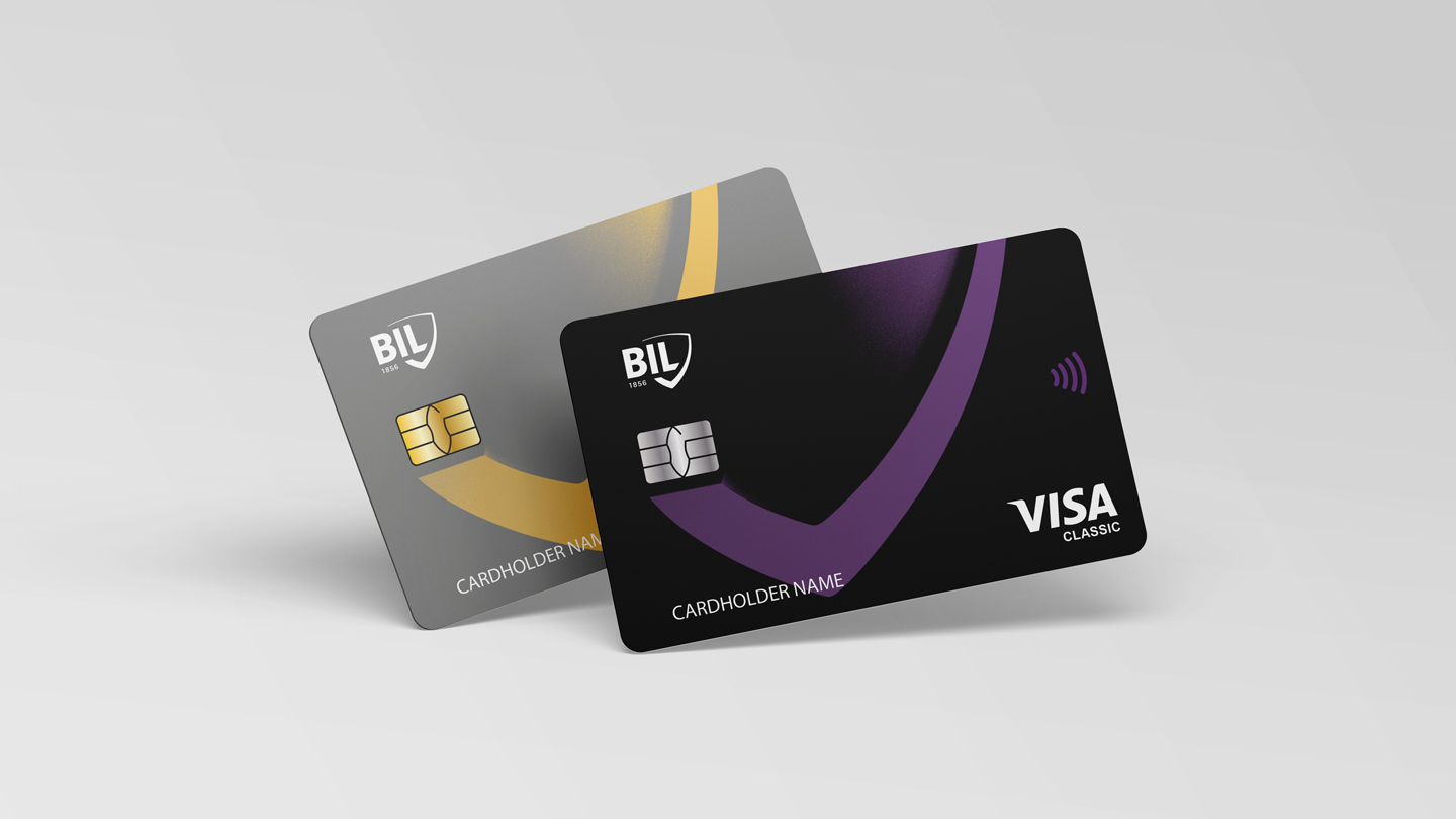 Vue des cartes Visa émises par la BIL. La carte Visa Classic horizontale est noire avec le motif décliné du logo écusson, en violet. La carte Visa Gold Business horizontale est grise avec le motif décliné du logo écusson, en jaune.