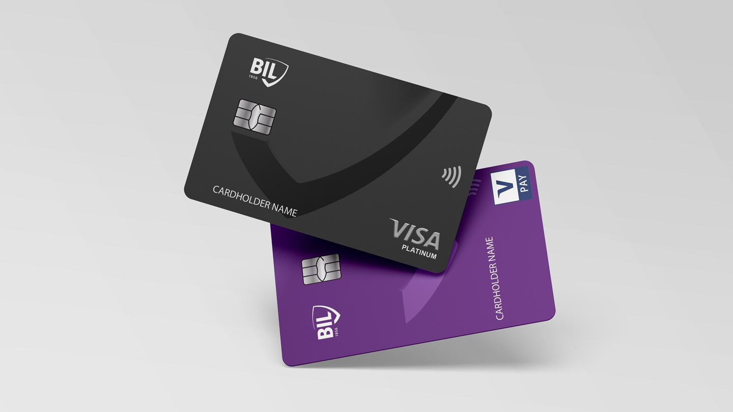 Vue des cartes Visa émises par la BIL. La carte Visa Platinum horizontale est gris foncé avec le motif décliné du logo écusson, en noir. La carte V Pay verticale est violet foncé avec le motif décliné du logo écusson, en violet clair.