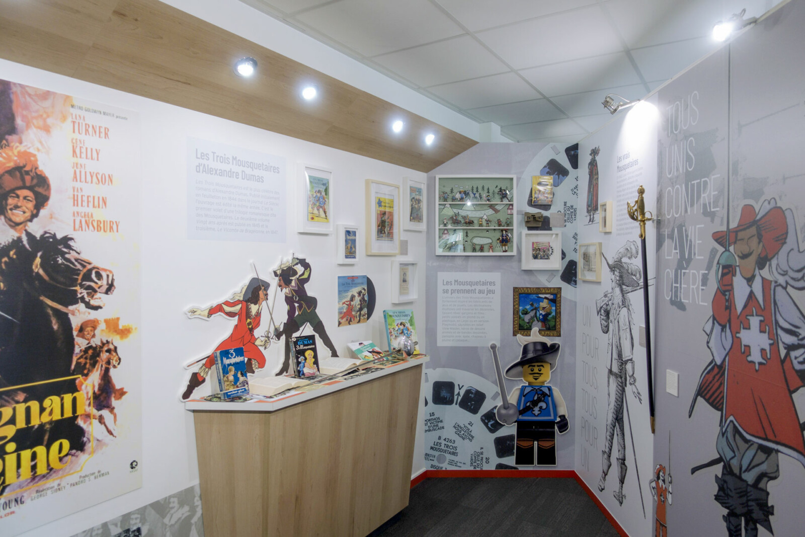 Vue d’ensemble de l’espace dédié à la représentation des Mousquetaires dans la culture populaire : affiche de film, roman, livre-disque, figurines, Lego…