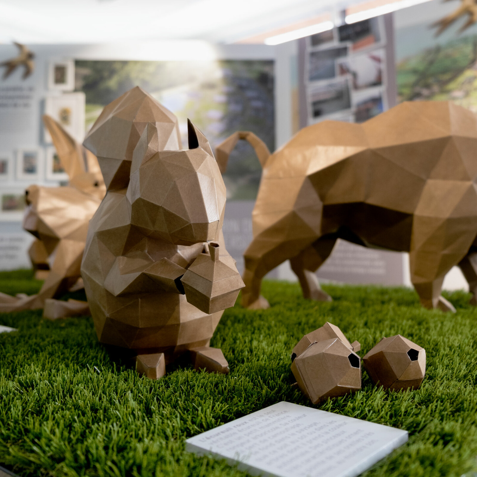 Vue zoomée sur un écureuil en paper craft, installé sur un gazon synthétique, au sein de l’exposition temporaire consacrée au Parc de Tréville, le siège des Mousquetaires.